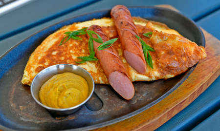 Delicious omelet with Bavarian sausages, restaurant serving.の写真素材