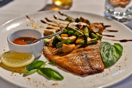 Fried sea bass on a bed of asparagus and mushrooms.