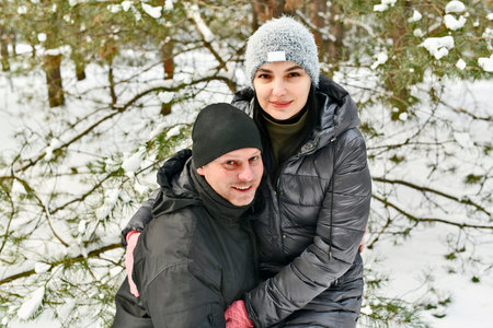 Two families walk in a winter snowy forest.