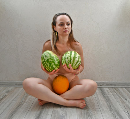Beautiful adult woman collects autumn harvest of vegetables and fruits in warm sunny weather.の写真素材