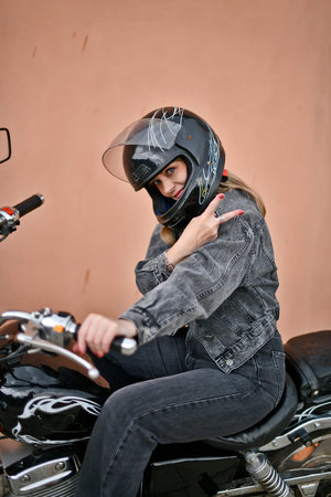 Woman in black denim suit and black helmet riding her chopper motorcycle on sunny summer day.の写真素材
