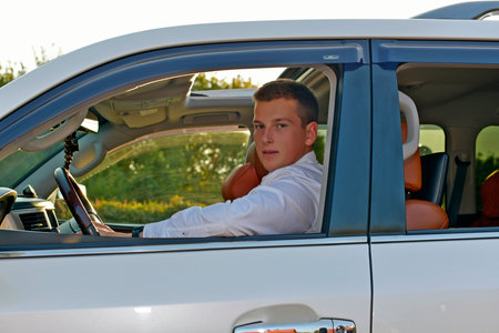 A young brother and sister are relaxing, driving around in a large white SUV. They're wearing...