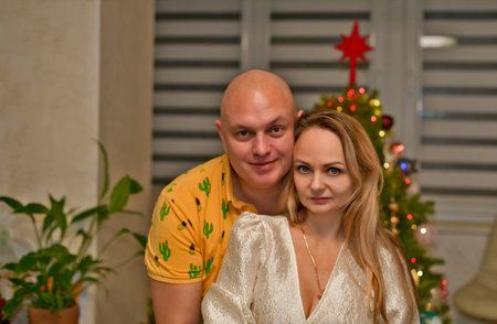 A man and a woman, a husband and wife, kiss and hug, take a photo near the New Year tree.の写真素材