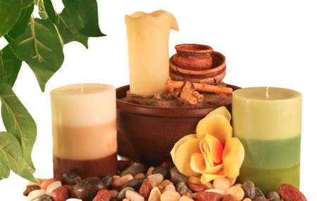 Two candles with a yellow flower sitting on pebblesの写真素材