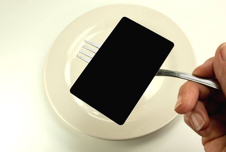 Blank black card on fork on white plateの写真素材