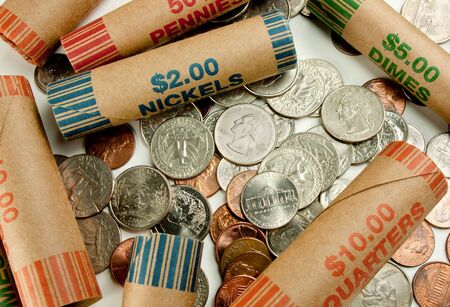 Coins laying with coin wrappers on tableの写真素材