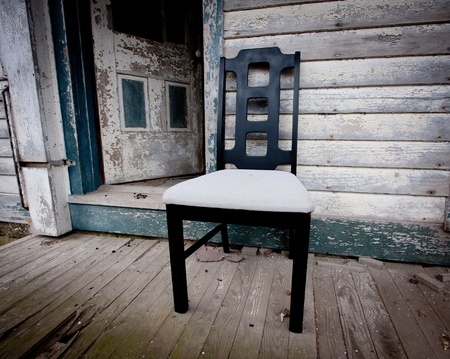 Chair sitting on porch at old abandon house with peeling blue paintの写真素材