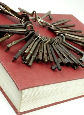 Set of antique keys sitting on top of a red hardcover bookの写真素材
