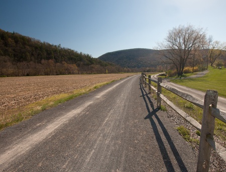 Gravel path along a wooden fence. Trees and mountians in the backgroundの写真素材