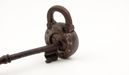 An old worn key inserted into a lock. Over white backgroundの写真素材