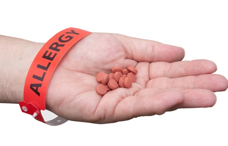 Hand holding pills and wearing a allergy medical id braceletの写真素材
