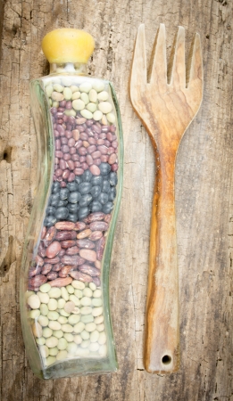 Beans in glass container on a wooden table with wooden forkの写真素材