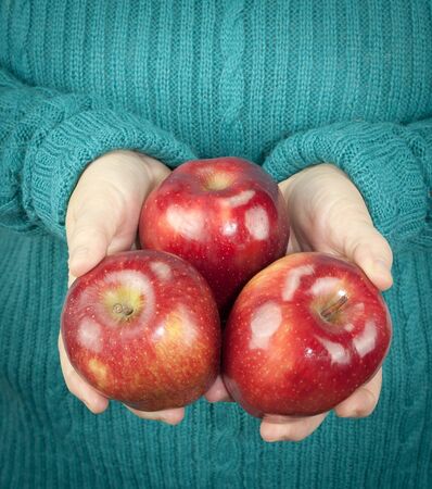 Woman holding three apples in her handの写真素材