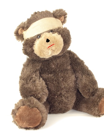 An injured stuffed bear wrapped in an ace bandage around his head isolated on whiteの写真素材