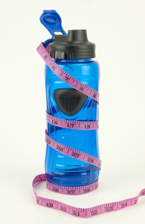 A purple weight measuring tape wrapped around a blue water bottle isolated on whiteの写真素材