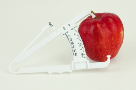A weight caliper tool measuring a red apple isolated on whiteの写真素材
