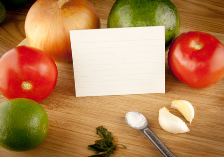 Ingredients sitting on top of a cutting board with a blank white recipe cardの写真素材