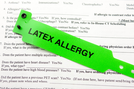 A green latex allergy patient bracelet on top of a hospital questionnaire paperworkの写真素材