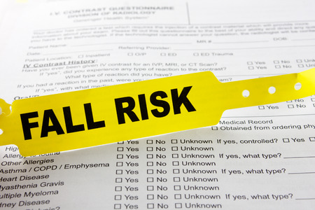 A yellow fall risk patient bracelet on top of a hospital questionnaire paperworkの写真素材