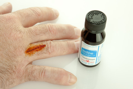 Finger with cut and iodine treatment on it with a bottleの写真素材