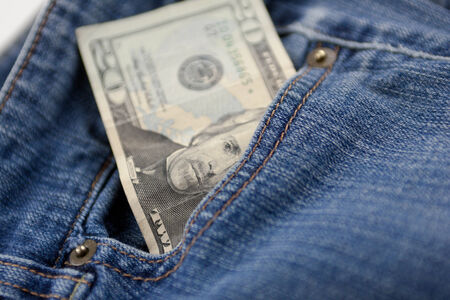 A twenty dollar bill sticking out the front pocket of denim blue jeansの写真素材