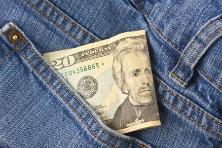 A twenty dollar bill sticking out the front pocket of denim blue jeansの写真素材