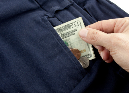 A twenty dollar bill sticking out the front pocket of dress jeans with coinsの写真素材