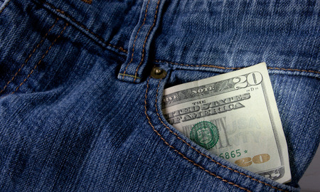A twenty dollar bill sticking out the front pocket of denim blue jeansの写真素材