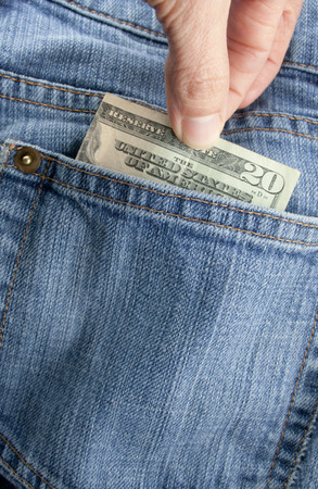 A person pulling a twenty dollar bill out of a denim blue jean back pocketの写真素材