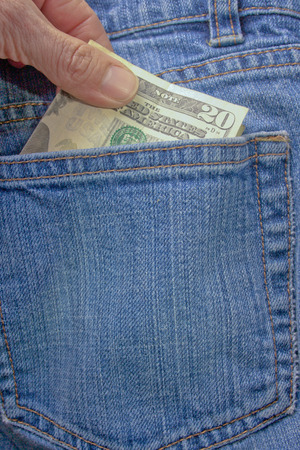 A person pulling a twenty dollar bill out of a denim blue jean back pocketの写真素材