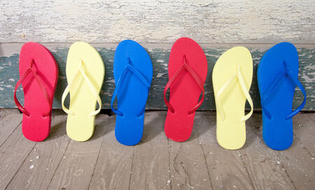 Multi colored flip-flops leaning against a houseの写真素材