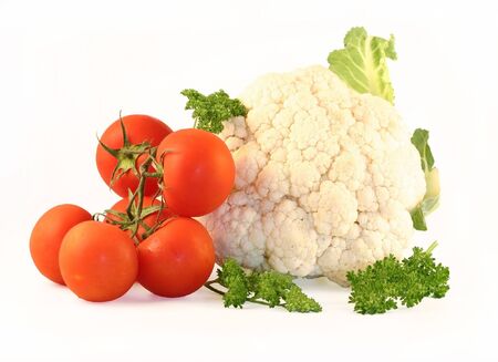 The cauliflower and tomatoes are photographed on a white background close up. Beside the parsley lays.の写真素材