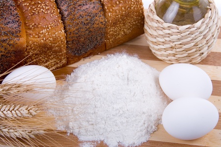 Fresh bread,  eggs,  flour  and  oil  on a wood  board