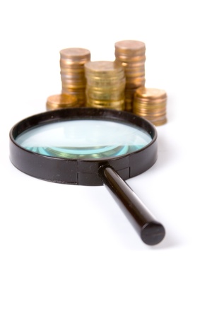 Piles of gold coins and magnifying glass on a white background の写真素材