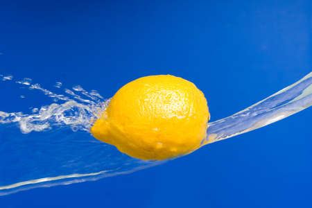 Fresh lemon  in the splashes of water on a  blue background の写真素材