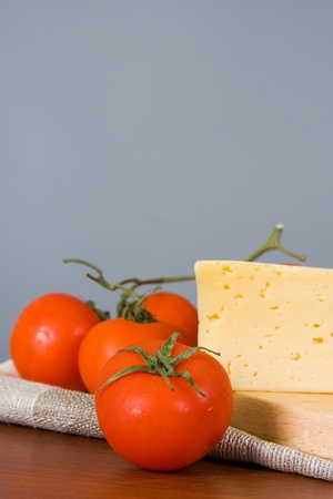 Yellow cheese with fresh tomatoes on gray background の写真素材