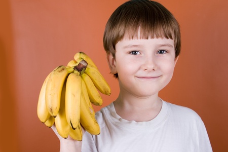 Portrait smiling boy with bananas on a brown backgroundの写真素材