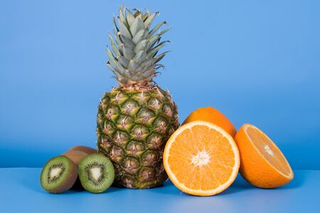 Pineapple, oranges and kiwi on a blue backgroundの写真素材