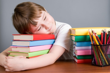 Tired boy sleeps on the books on a gray backgroundの写真素材