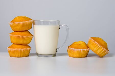 Glass of milk and cupcakes on gray backgroundの写真素材