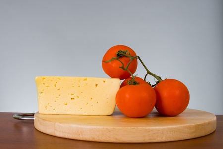 Yellow cheese with fresh tomatoes on gray background の写真素材