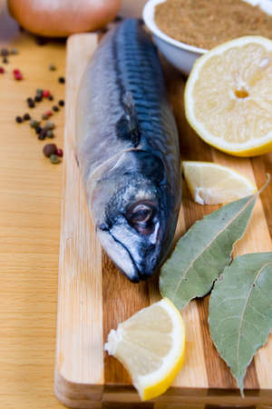 Raw mackerel with lemon, spices and vegetables on a wooden table
