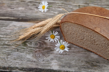 Bread, ears and daisies on a wooden table. Still life.の写真素材