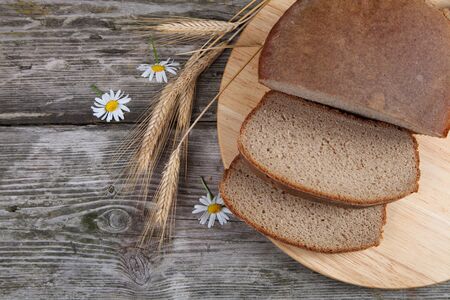 Bread, ears and daisies on a wooden table. Still life.の写真素材