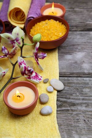 Spa concept: soap, salt for baths, a flower and towels on a wooden backgroundの写真素材
