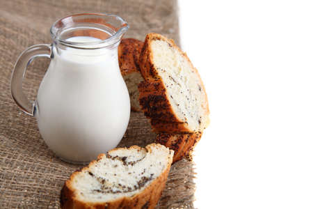 Glass jug with milk and bread on a brown fabric on a white background の写真素材