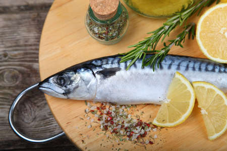 Raw fish with lemon and rosemary on a wooden boardの写真素材