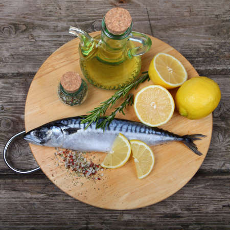 Raw fish with lemon and rosemary on a wooden boardの写真素材