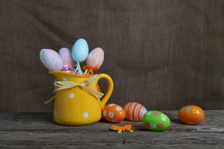 Easter eggs in a yellow jug on the wooden tableの写真素材