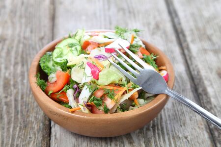 Vegetable salad in a wooden bowl on a wooden backgroundの写真素材